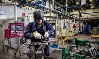  Waupaca铸造 employee inspects iron castings as they make their way through the mill room